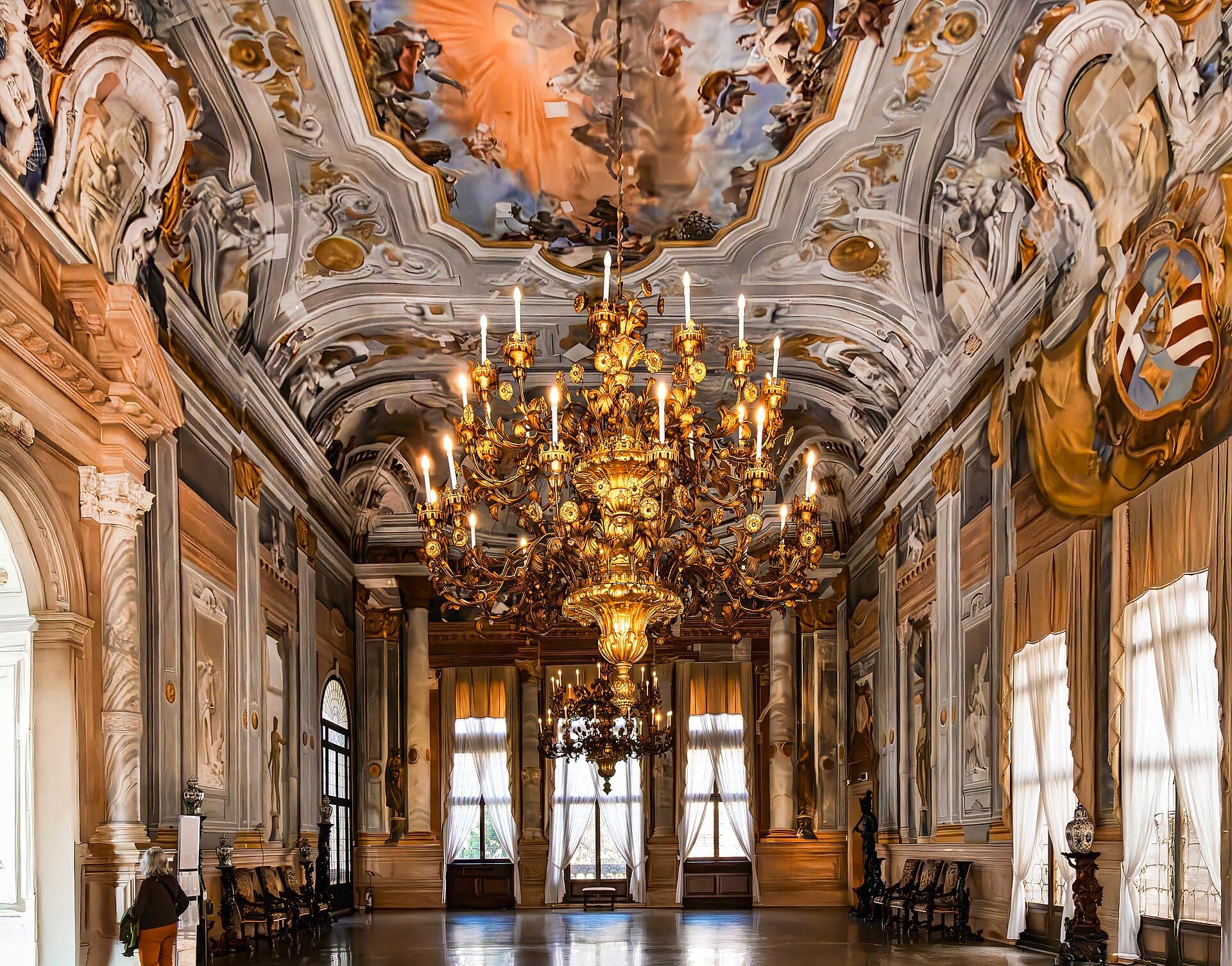 A gilded ballroom with a chandelier, empty before an event